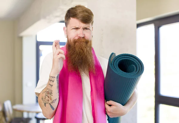 红头发的男人交叉手指 希望好运与瑜伽垫 健身概念 — 图库照片