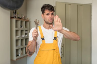 Genç ve yakışıklı adam ciddi görünüyor. Avuç içi gösteriyor. Durdurma hareketi yapıyor. Becerikli adam kavramı