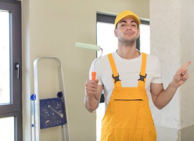 Genç yakışıklı adam neşeyle gülümsüyor, mutlu hissediyor ve bir tarafı işaret ediyor. resim ev kavramı