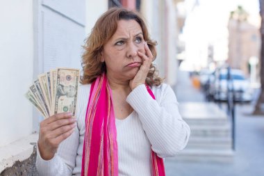 Orta yaşlı, güzel bir kadın bıkkın, yorgun ve uykulu hissediyor. Dolar banknotları konsepti