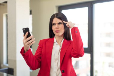 Güzel genç bir kadın şaşırmış görünüyor, yeni bir düşünce, fikir ya da konsept fark ediyor. akıllı telefon kavramı