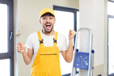 Genç yakışıklı adam şok olmuş hissediyor, gülüyor ve başarıyı kutluyor. Becerikli adam kavramı