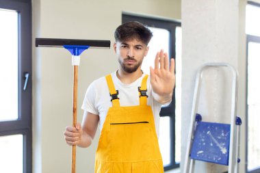 Genç ve yakışıklı adam ciddi görünüyor. Avuç içi gösteriyor. Durdurma hareketi yapıyor. pencere temizleme konsepti