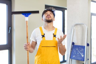 Genç yakışıklı adam ellerini havaya kaldırarak çığlık atıyor. pencere temizleme konsepti