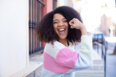 Afro-Amerikan güzel kadın kendini mutlu, tatmin olmuş ve güçlü hissediyor, kaslı ve formda, spor salonundan sonra güçlü görünüyor.