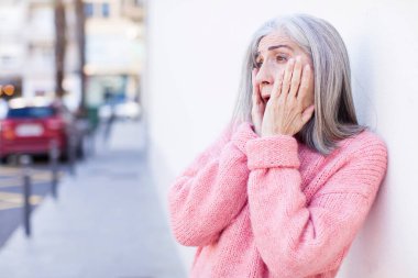 Yaşlı, emekli, güzel, beyaz saçlı, mutlu, heyecanlı ve şaşırmış bir kadın.