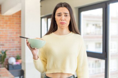 Oldukça genç bir model üzgün ve mızmızlanıyor. Mutsuz bir bakışı ve ağlaması var. Kahvaltı kasesi konsepti