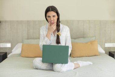 Ağzı ve gözleri açık ve elleri çenesinde güzel genç bir manken. dinlenme ve gecelik konsepti