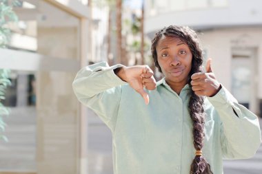 Afro güzel siyah kadın kafası karışık, bilgisiz ve kararsız hissediyor, iyiyi ve kötüyü farklı seçeneklerle tartıyor.