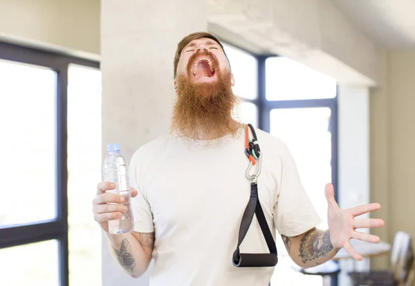 红头发的男人双手举着水瓶在空中尖叫 健身概念 — 图库照片