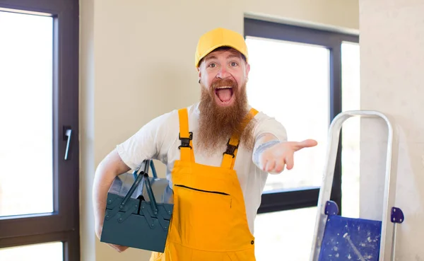 赤い髪の男は喜んで笑みを浮かべて家を修復する概念を提供または示す 便利屋のコンセプト — ストック写真