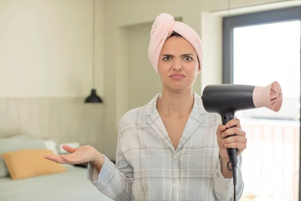 stock image young pretty woman shrugging, feeling confused and uncertain. hair dryer concept