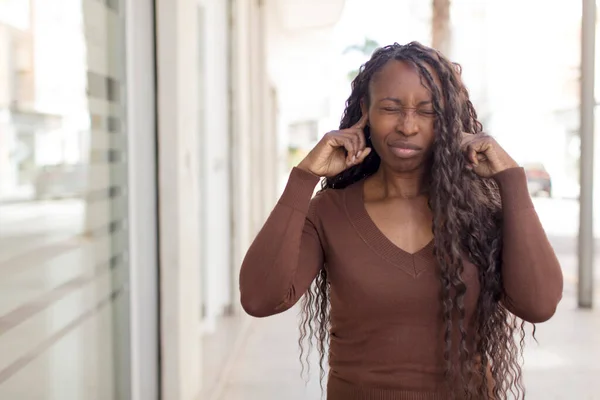 黒人女性のアフロは怒りとストレスといらいらを感じ耳の両側を耳の聞こえない音や音や大きな音楽で覆い — ストック写真