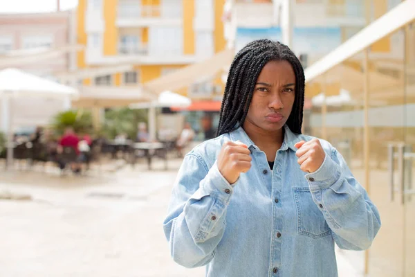 afro pretty black woman looking confident, angry, strong and aggressive, with fists ready to fight in boxing position