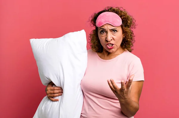 パジャマのナイトウェアと枕を着て怒っていらいらし不満そうな中年女性です — ストック写真