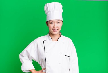 Güzel Asyalı kadın mutlu bir şekilde gülümsüyor, eli kalçasında ve kendinden emin. restoran şefi konsepti