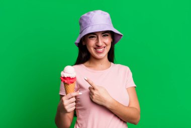 Neşeli bir şekilde gülümsüyor, mutlu hissediyor ve bir tarafı işaret ediyor. dondurma ve yaz konsepti