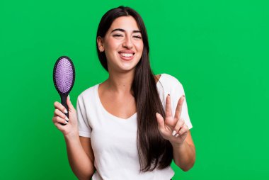 Gülümsüyor ve arkadaş canlısı görünüyor, üç numarayı gösteriyor. saç tarağı konsepti