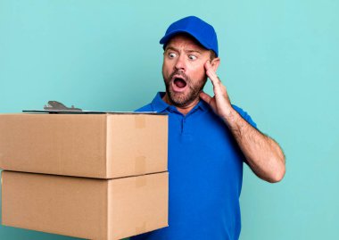 Orta yaşlı bir adam mutlu, heyecanlı ve şaşırmış hissediyor. Paker teslimatçısı. Paketçi teslimatçı