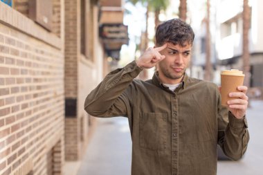 Genç yakışıklı adam şaşırmış görünüyor, yeni bir düşünce, fikir ya da konsept fark ediyor. kahve konseptini kaldır.