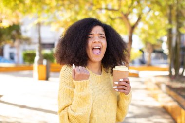 Oldukça afro siyahi bir kadın kızgın, sinirli ve sinirli görünüyor. kahve konseptini kaldır.