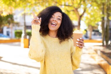 Güzel afro siyah kadın bir fikri fark ettikten sonra mutlu ve heyecanlı bir dahi gibi hissediyor. kahve konseptini kaldır.