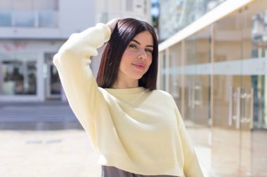 Genç, güzel bir kadın neşeli ve sıradan bir şekilde gülümsüyor, olumlu, mutlu ve kendinden emin bir bakışla göğüs göğüse tutuşuyor.