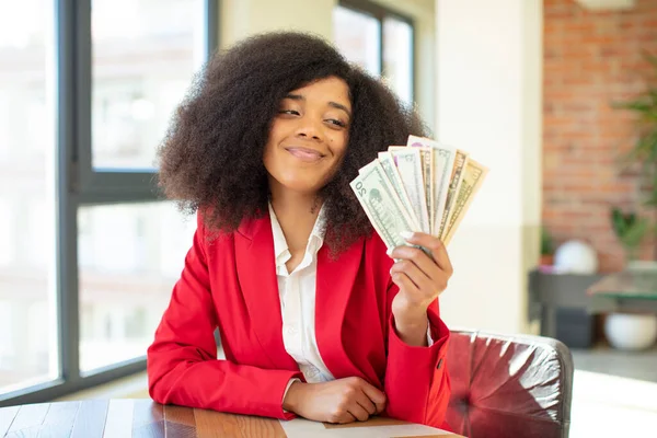 pretty afro black woman smiling and looking with a happy confident expression. dollar banknotes concept