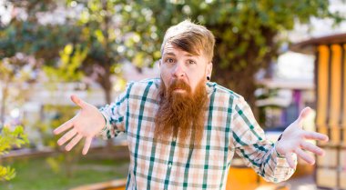 red hair bearded man feeling clueless and confused, having no idea, absolutely puzzled with a dumb or foolish look