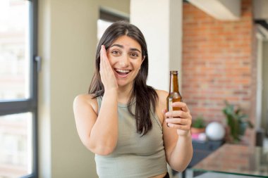 Genç bir kadın inanılmaz bir şey karşısında kendini mutlu ve şaşkın hissediyor. bira şişesi