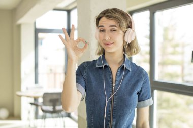 Güzel bir kadın kendini mutlu hissediyor, iyi bir jestle onaylıyor. kulaklıklar ve müzik konsepti