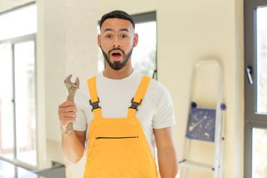 Arap yakışıklı adam, Arap adam şok olmuş ve şaşırmış hissediyor. İngiliz anahtarı olan bir tamirci.