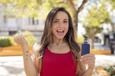 Güzel kadın şokta, gülüyor ve başarıyı kutluyor. vaper konsepti