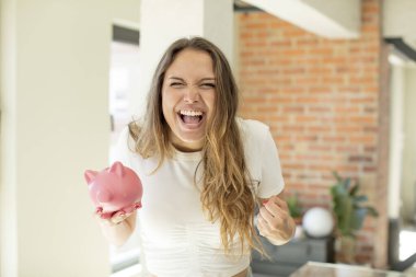 Güzel bir kadın sinirli, sinirli ve sinirli görünüyor. Domuz kumbarası konsepti