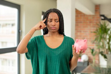 Siyah afro kadın şaşırmış görünüyor, yeni bir düşünce, fikir ya da konsept fark ediyor. Domuz kumbarası konsepti