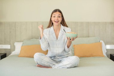 Genç ve güzel bir kadın şokta, gülüyor ve başarıyı kutluyor. kahvaltı kavramı