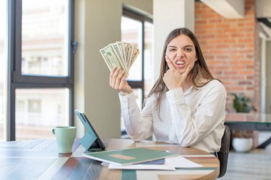 young pretty woman with mouth and eyes wide open and hand on chin. telecommuting concept