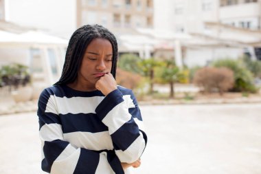 Afro güzel siyah kadın ciddi, düşünceli ve endişeli hissediyor, elleri çenesine bastırılmış bir şekilde yan bakıyor