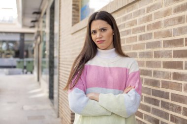 pretty young adult woman feeling displeased and disappointed, looking serious, annoyed and angry with crossed arms