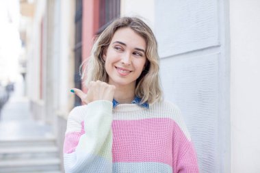 Güzel bir kadın neşeyle gülümsüyor ve yan taraftaki fotokopi alanını gösteriyor, mutlu ve tatmin olmuş hissediyor.