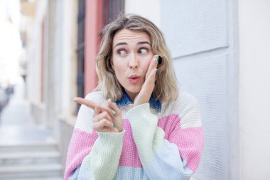 Güzel bir kadın şok olmuş bir ifadeyle şaşırır ve yüzünü gösterir.