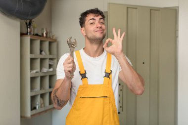 Genç yakışıklı adam kendini mutlu hissediyor, iyi bir jestle onaylıyor. Becerikli adam kavramı