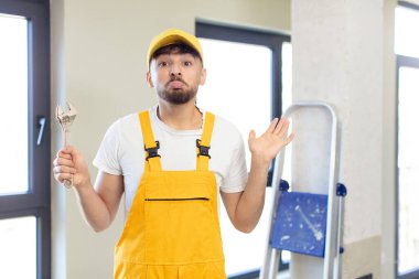 Genç yakışıklı adam omuz silkiyor, kafası karışık ve kararsız. Becerikli adam kavramı