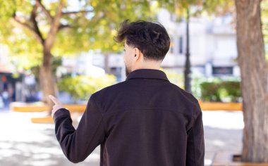 Genç yakışıklı adam dikiz aynası ve fotokopi alanı üzerinde duran ve objeyi işaret eden