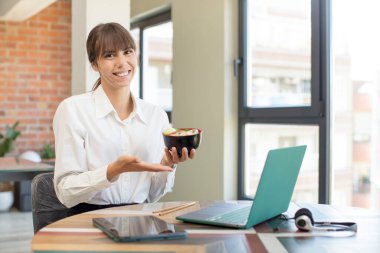 Genç, güzel bir kadın neşeyle gülümsüyor, mutlu hissediyor ve bir konsept gösteriyor. ramen kasesi konsepti