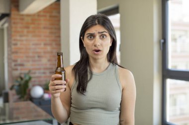 Genç bir kadın kendini çok şaşırmış ve şok olmuş hissediyor. bira şişesi