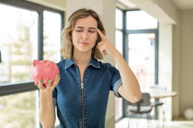 Güzel kadın şaşırmış görünüyor, yeni bir düşünce, fikir ya da konsept fark ediyor. Domuz kumbarası konsepti