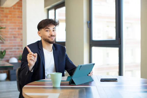 stock image young handsome man smiling cheerfully, feeling happy and pointing to the side. touch screen pad concept