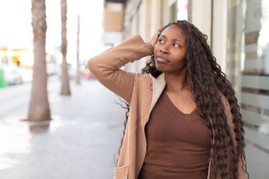 afro güzel siyah kadın şaşkın ve şaşkın hissediyor, başını kaşıyor ve yan bakıyor