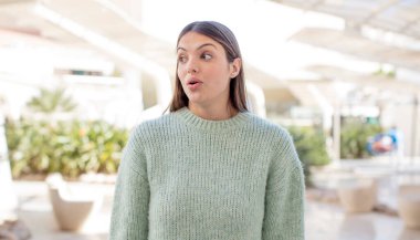 Genç, güzel bir kadın şaşırmış ve şaşırmış hissediyor. Şaşırmış ve ağzı açık bir şekilde bir yandan boşluğu kopyalamak istiyor.